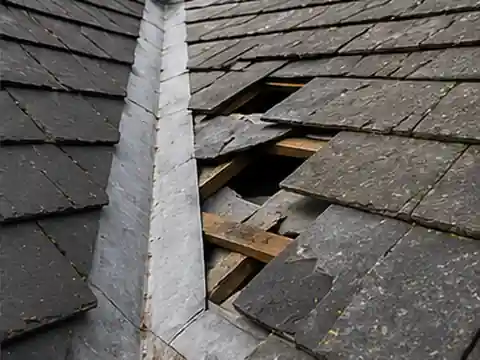 Damaged slates beside a roof valley where water can enter